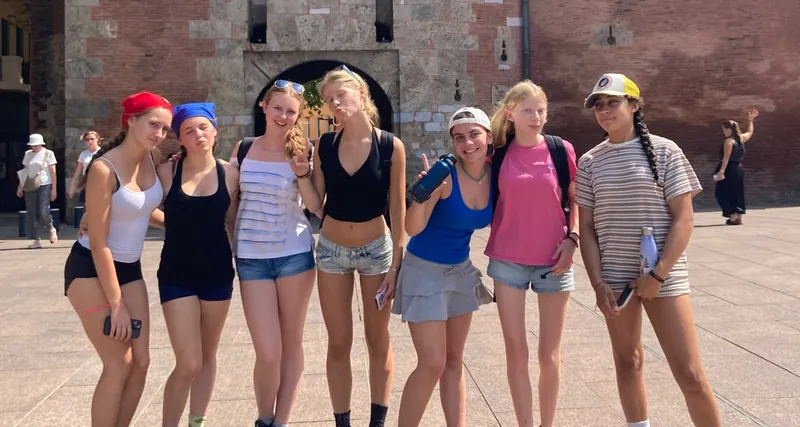 Un groupe de sept jeunes serrées les unes contre les autres, posant devant le Castillet de Perpignan
