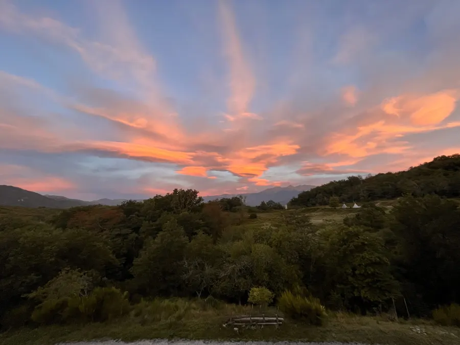 Cielo rosa y naranja al atardecer sobre los árboles y las colinas que rodean Le Noell