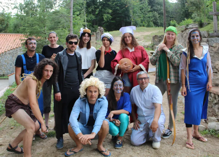 Une équipe d’animateurs en costumes de théâtre posant sur un chemin, devant les ruines et les arbres