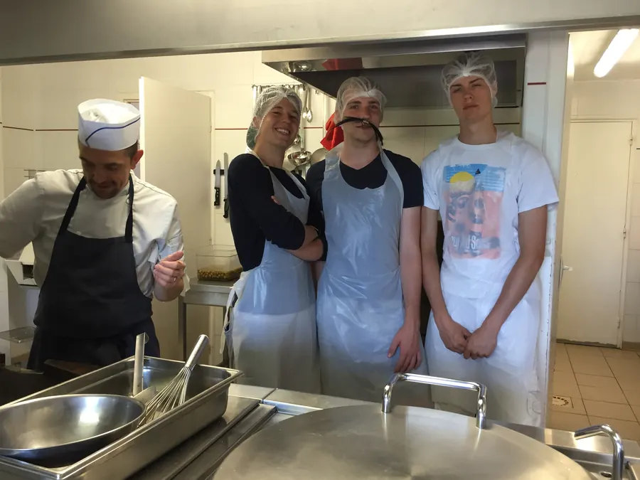 Le chef cuisinier et trois jeunes de l’équipe en tablier et charlotte, dans la cuisine du Noell