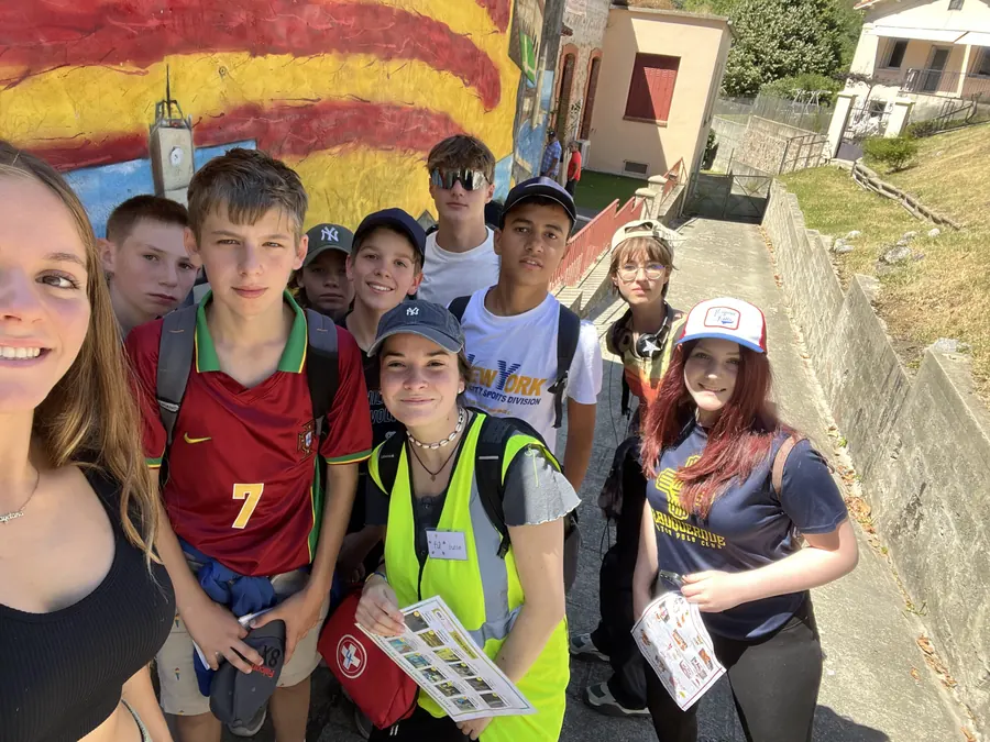 Des jeunes avec casquettes et gilets jaunes pendant une sortie, en train de poser pour un selfie dans une rue du village