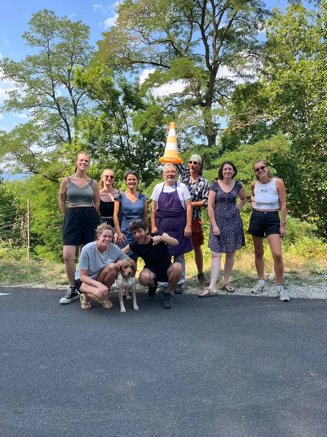 Un groupe de huit personnes et un chien posant sur la route, devant des arbres
