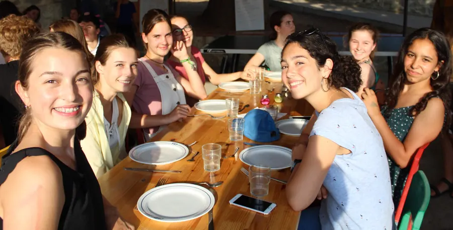 Des jeunes souriants attablés pour le repas sur la terrasse