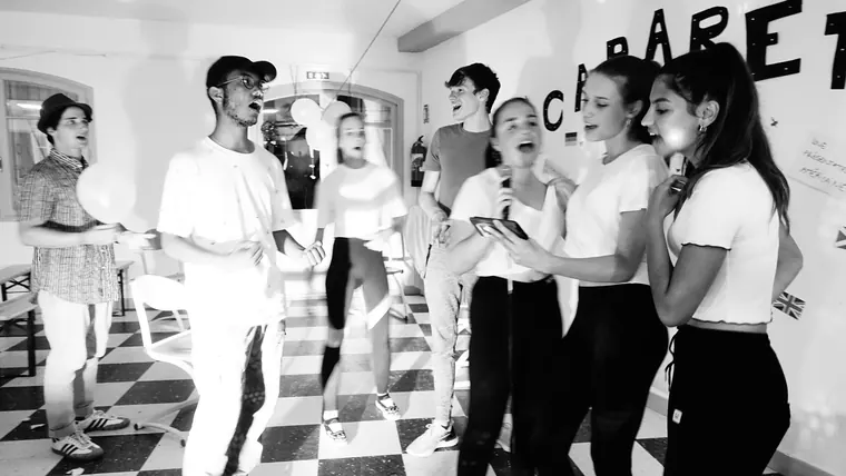 Des jeunes qui chantent ensemble pendant une soirée cabaret, photo en noir et blanc