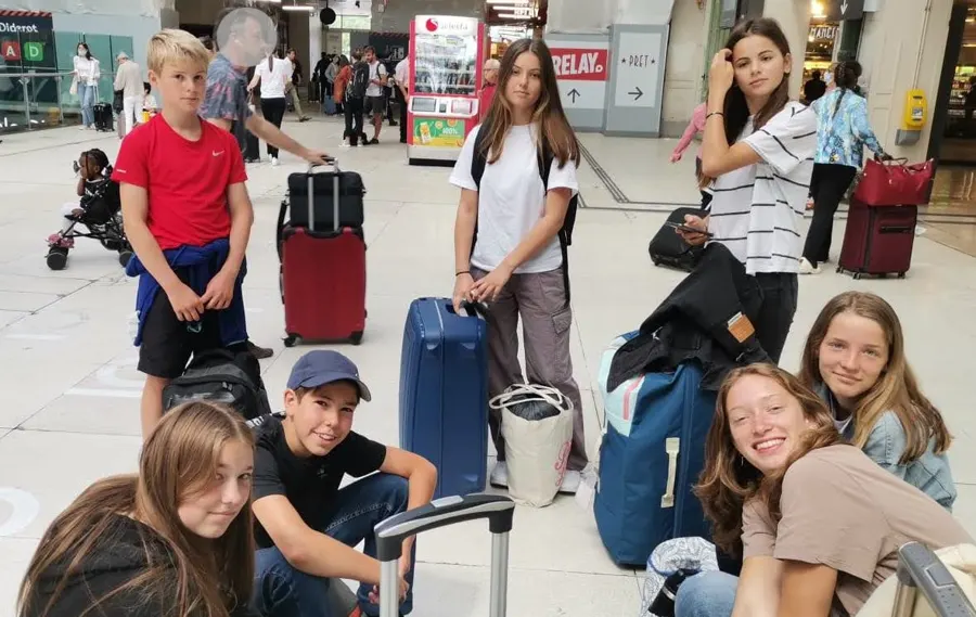 Des jeunes avec leurs valises dans le hall de la gare, avant de prendre le train