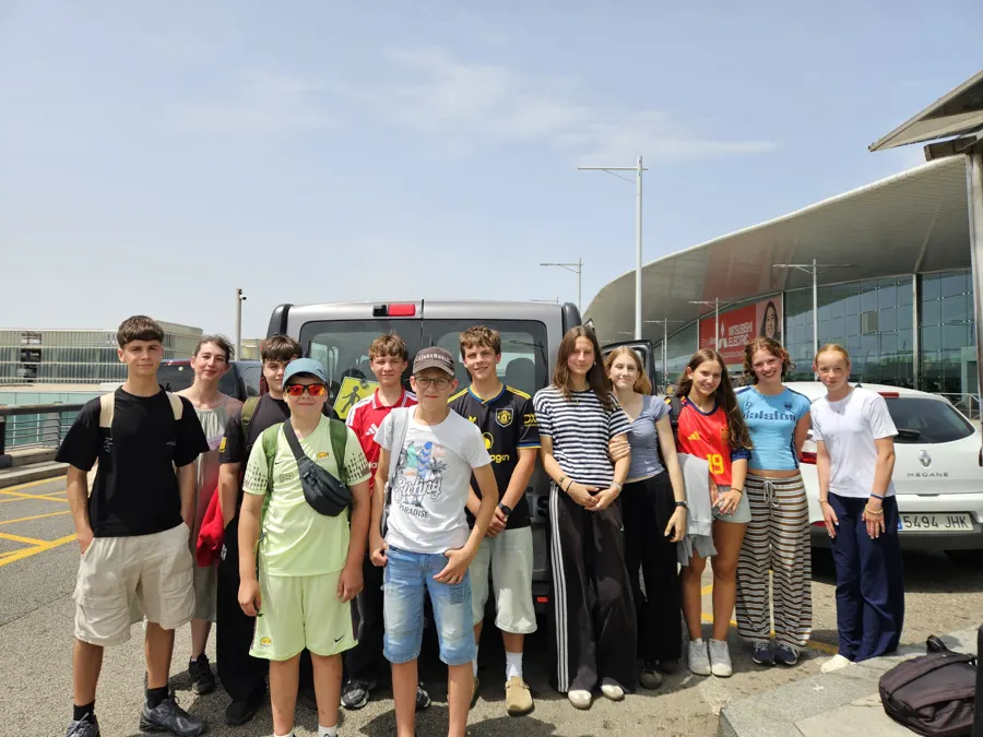 Un groupe de jeunes posant devant un minibus, sur le parking de l’aéroport
