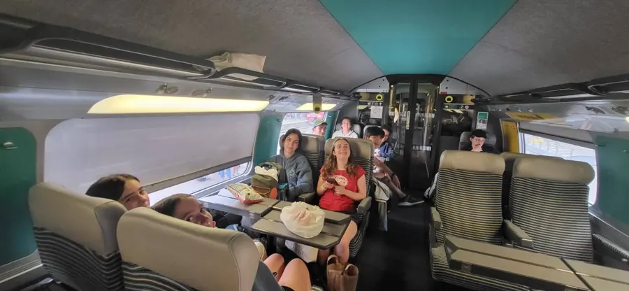 Des jeunes installés autour des tables dans une rame de train