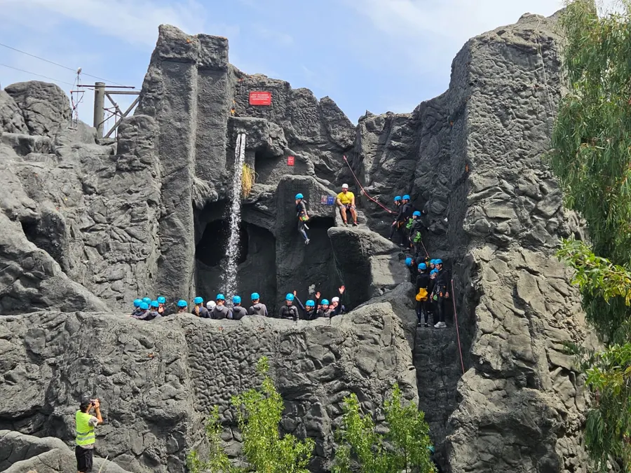 Jugendliche mit Helm bahnen sich ihren Weg über die Felsen und Wasserpassagen des Canyoning-Parks