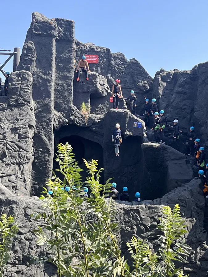 Jugendliche mit Helm klettern auf den Felsen des Canyoning-Parks